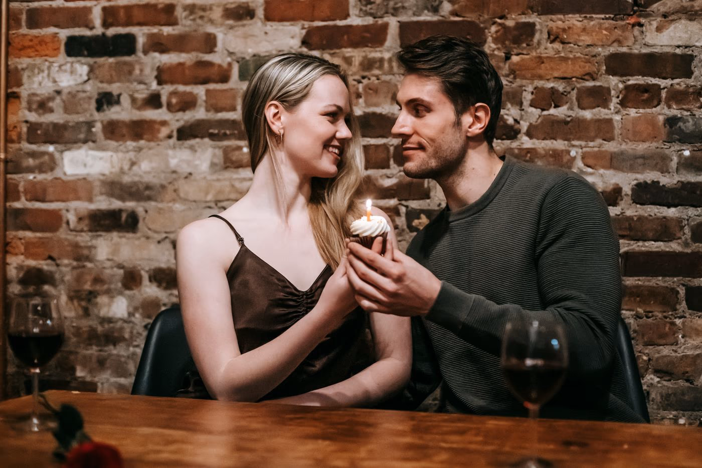 A couple sharing a candlelit cupcake and wine during a birthday date